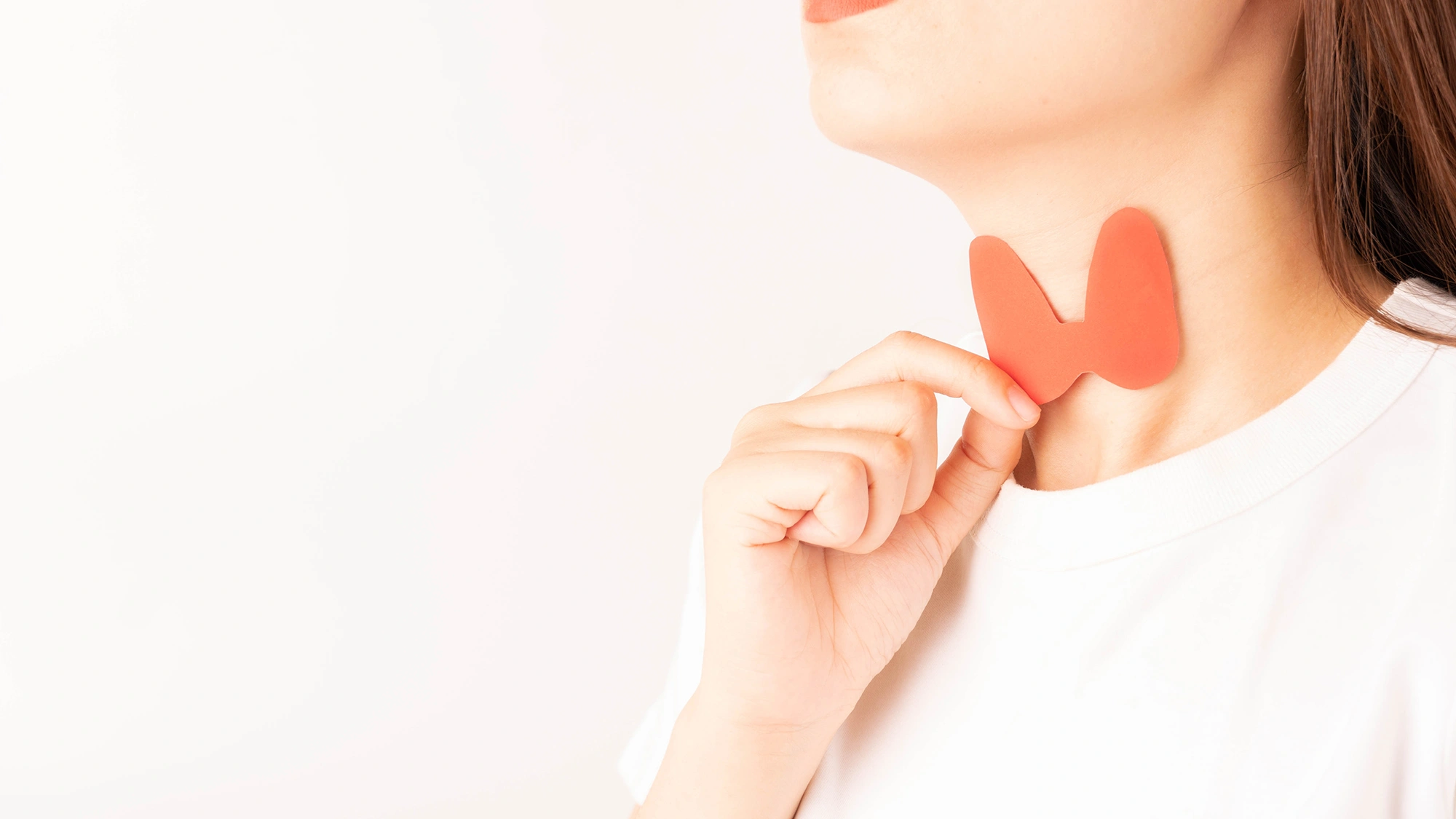 A woman placing a thyroid gland-shaped paper against her neck.