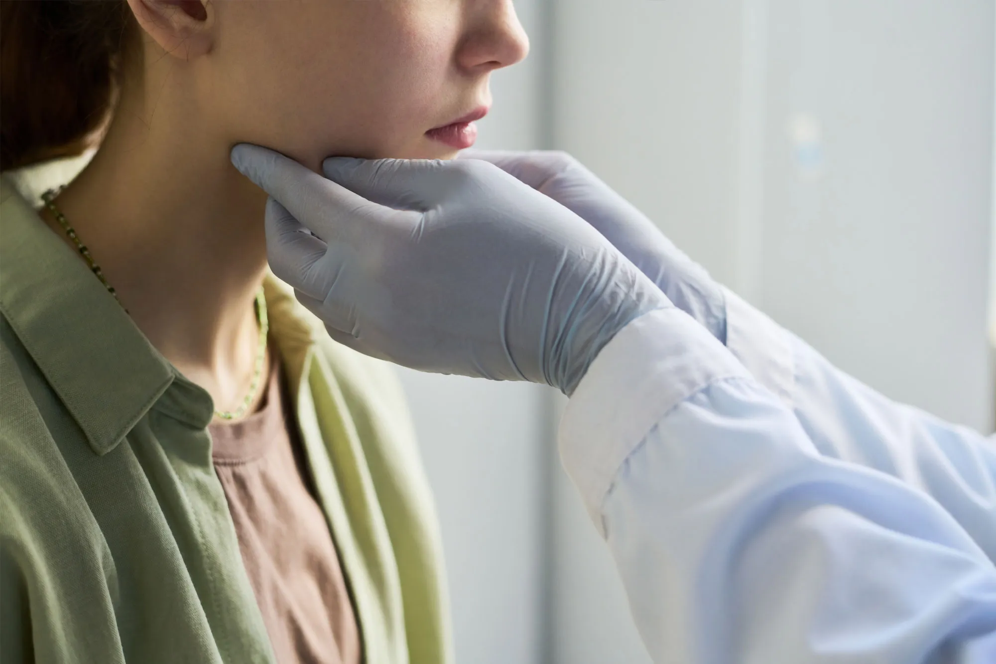 Healthcare professional examining a patient’s neck, checking for swelling or pain during a medical assessment.