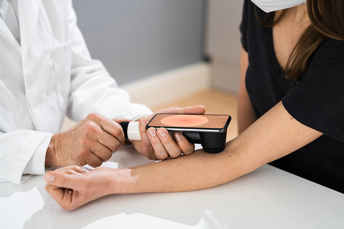 Doctor closely examining a woman’s pigmented skin spot, assessing for signs of melanoma or other skin cancer.